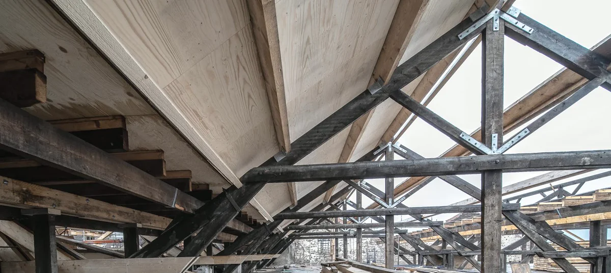 Charpente sous toiture avec poutres en bois et éléments métalliques